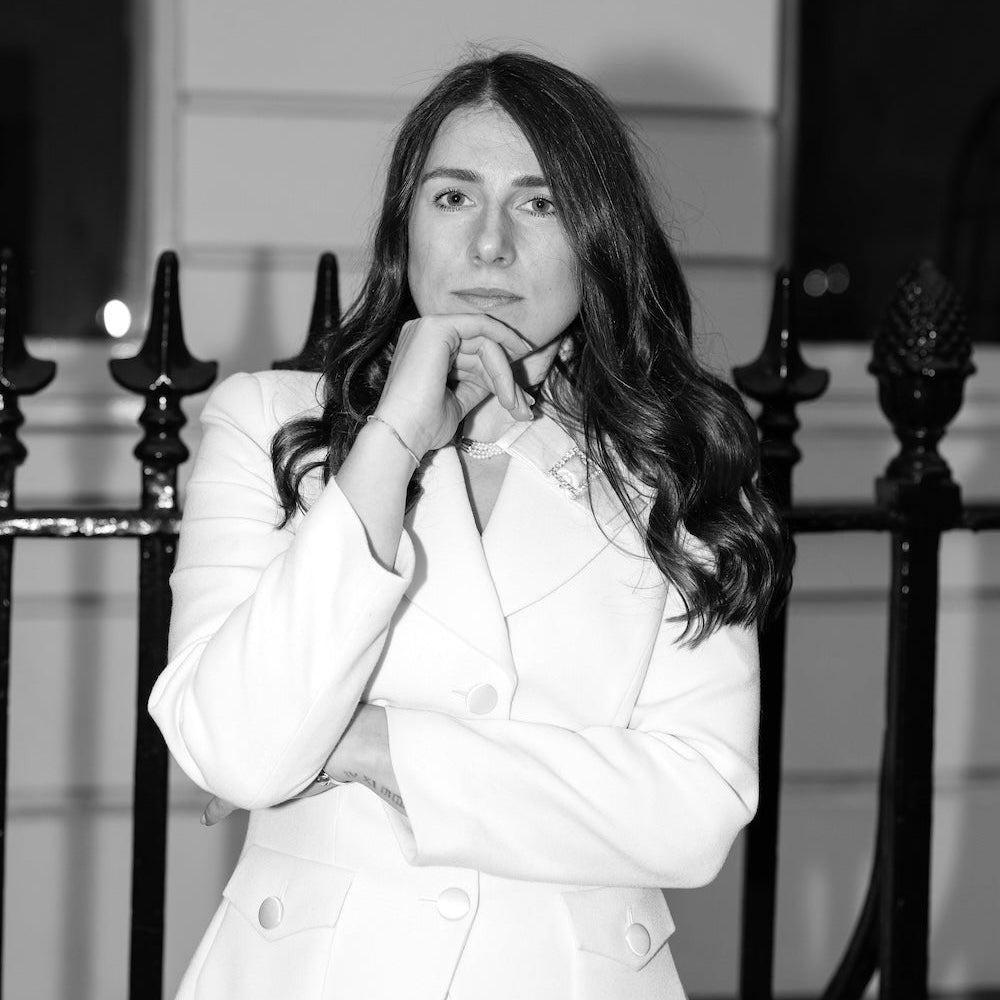 Veronica Russo in white suit against black railings